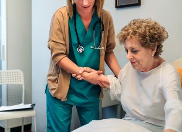 Caregiver helping elderly patient to get out of bed