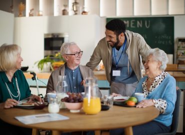 Group of cheerful seniors enjoying breakfast in nursing home care center
