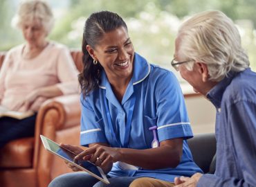 senior-couple-at-home-with-man-talking-to-female-nurse-or-care-worker-using-digital-tablet.jpg